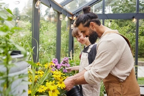 Mann und Frau kümmern sich um Blumen in Gewächshaus